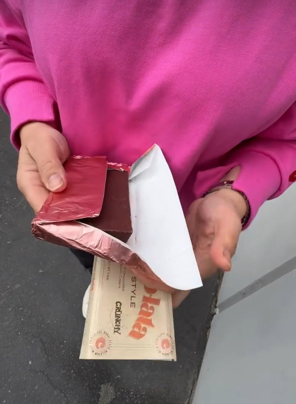 Person holding a package with a visible brand name on a gray surface